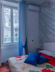 那不勒斯B&B Giosuè的一间卧室配有一张带蓝色枕头的床和一扇窗户。