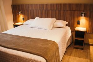 格拉玛多Hotel Fioreze Centro的一间卧室设有一张大床和两个床头柜