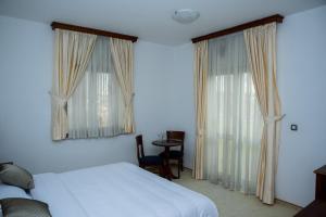 柳布什基哈姆酒店的一间卧室设有一张床和两个大窗户