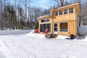 巴瑟斯特Cozy Cabin for Intimate Wilderness Escape的雪中带两把红色椅子的房子