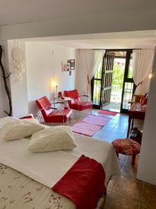 皮萨拉B&B Finca Alegria de la Vida的一间卧室配有一张大床和红色椅子