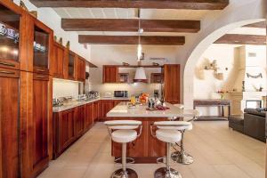 加斯利LeVecca Village House 1 - Gladiola的一个带木柜的厨房和一个带酒吧凳的岛屿