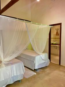 托兰克索Pousada Villa Bahia的卧室配有2张带白色窗帘的床