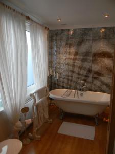 锡豪西斯Ugiebrae House Bed & Breakfast的带浴缸的浴室和窗户。