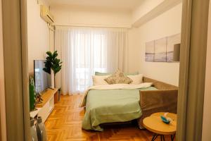 雅典Newly Renovated Apartment 7 min walk from Acropolis的一间卧室配有一张床、一张沙发和一台电视