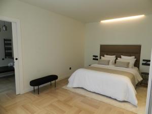 马尔托雷尔HOTEL MANEL的一间白色卧室,配有一张床和一张黑色凳子