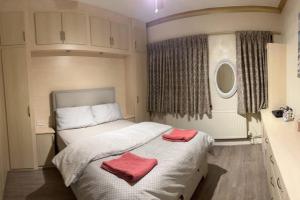 罗姆福特Amazing 4 Bedrooms family home with free parking的一间卧室配有一张带两个红色毛巾的床