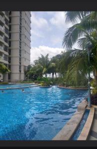 新山Royal Strand Danga Bay Abang Payung的一座棕榈树大型游泳池和一座建筑