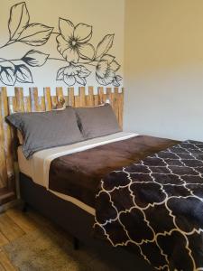 蒙特韦尔迪Recanto das Glicínias的卧室配有一张挂着花壁画的床。