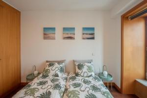 马托西纽什Porto Metro-At-Home Apartment的一间卧室配有一张床,墙上有三幅画作