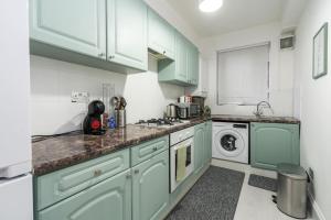 伦敦Exceptional 5 stars flat in lovely location的厨房配有绿色橱柜、洗衣机和烘干机