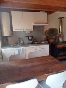 MiremontMaisonnette chaleureuse de 35m2的厨房配有木桌和白色橱柜。