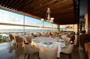 萨尔瓦多Cloc Marina Vista Mar p/ a Baía de Todos os Santos的一间设有白色桌椅和窗户的用餐室