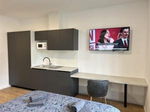 萨格勒布Park Maksimir Apartments的一个带水槽的厨房和墙上的电视