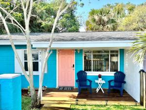 可可比奇Beach Bungalow in downtown Cocoa Beach的蓝色和白色的房子,配有粉红色的门和两把椅子