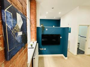 诺丁汉Lovely Studio Apartment in the Heart of Nottingham的客厅设有蓝色的墙壁和电视。