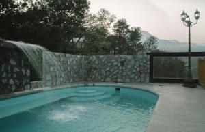 希利特拉Hotel Posada San Agustin的一个带石墙和瀑布的游泳池