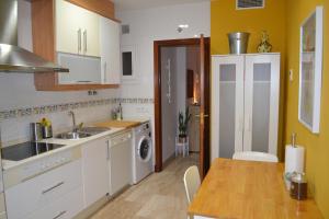 加的斯Apartamento Posidonia Free Parking的厨房配有白色橱柜、桌子和水槽。