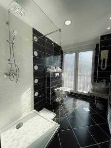 萨拉热窝Hotel City View Deluxe的黑白浴室设有淋浴和水槽