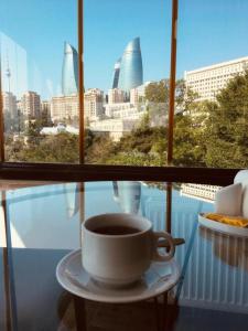 巴库City Walls Hotel的坐在窗前的桌子上喝杯咖啡