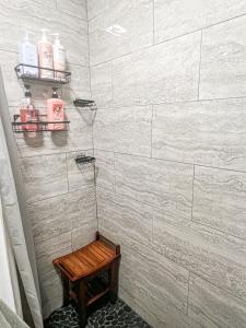 Cozy and Renovated 3 Bedroom Home的配有白色瓷砖墙壁和木凳的淋浴间