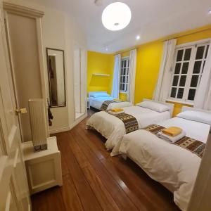基多开曼酒店的配有黄色墙壁和木地板的客房内的三张床