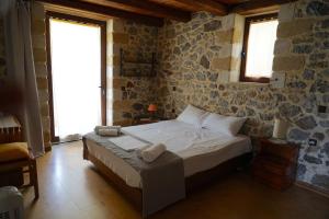 帕琉乔拉Elpida Country House -Paleochora-Anidri的石墙客房的卧室配有床