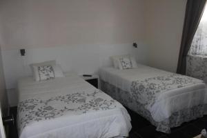 马达莱纳Moradia Familiar NovaVista - T3的一间卧室配有两张带白色床单的床