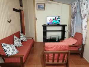 金特罗Cabaña "Descanso playero"的客厅配有2张红色沙发和电视