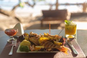 PochoteLos Vivos Beachfront Experience的肉,蔬菜和饮料的盘子