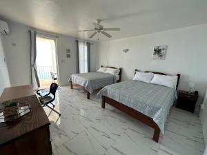 罗索ElDorado Guesthouse的一间卧室配有两张床、一张桌子和吊扇