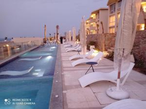 艾因苏赫纳Il monte galala Sea view Chalet المونت جلاله的游泳池旁的一排白色椅子