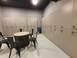 新山My Capsule Hotel的更衣室配有椅子、桌子和橱柜