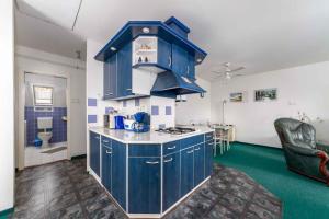巴拉顿博格拉尔House and Apt in Balatonboglar 42692的一间铺有绿色地板并配有蓝色橱柜的厨房