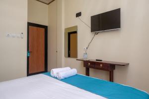 日惹Sans Hotel Kumbang Yogyakarta by RedDoorz的卧室配有一张床铺,墙上配有电视