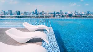 金边21B No.1 Best Location In Phnom Penh Capital, Swimming Pool & Gyms的两把白色椅子坐在游泳池边