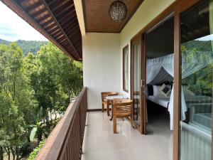 姆杜克Munduk Sari Resort的阳台配有床和桌椅