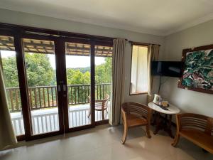 姆杜克Munduk Sari Resort的客厅设有带滑动玻璃门的阳台