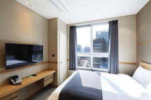 首尔The Stay Classic Hotel Myeongdong的酒店客房设有一张床和一个大窗户