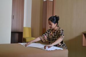 日惹茹玛康婷家庭旅馆的女人把毛巾放在床上