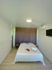 帕皮提Temana Airport Faa'a,Tahiti的卧室配有带鲜花的白色床