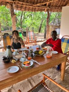 KisakiLemara Eco Camp的坐在餐桌旁吃饭的男人和女人