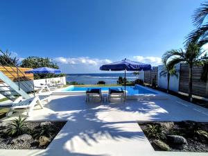 石垣岛Ocean View Ishigaki的一个带椅子和遮阳伞的游泳池以及大海