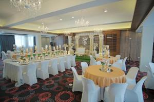 马尼拉奎松市马勒卡费萨尔酒店的宴会厅配有桌子、白色椅子和吊灯