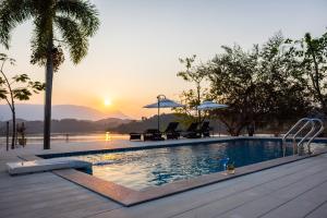 万荣萨图楠姆比奇度假村的一个带椅子的游泳池,享有日落美景