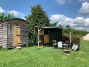 奥斯威斯Willowdene shepherds hut的院子中的小棚子和桌椅