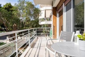 雅典Flisvos Marina refurbished apartment的阳台配有白色的桌椅
