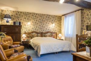 雷普隆吉斯Hostellerie Sarrasine - Mâcon Est的一间卧室配有一张床和一把椅子