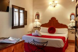 格拉纳达卡萨德卡皮特那萨利酒店的一间卧室配有一张带红色毯子的大床