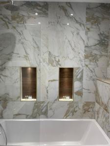 伦敦公园大道酒店 的浴室配有白色浴缸和大理石墙。